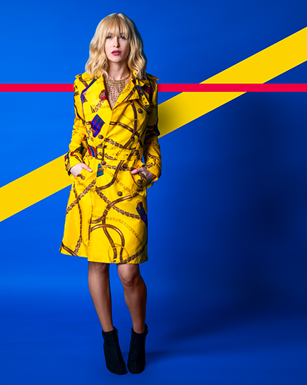 Model mit gelbem Mantel auf blauem Hintergrund