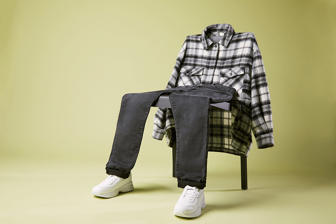 Herrenoutfit inszeniert auf einem Stuhl Sneaker Hose Hemd
