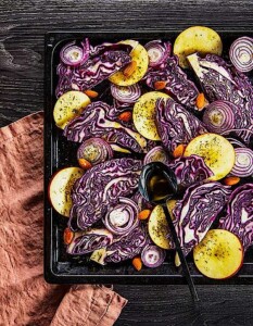 Lila Kohl mit Zwiebeln und Apfel auf Backblech